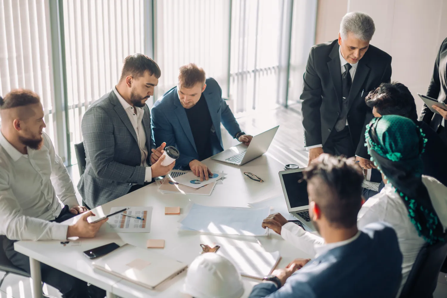 Mature old Chief Executive presents a young male speaker that is supposed to conduct a business presentation while standing in the board room with panoramic windows.